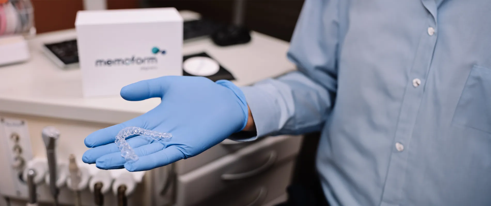 Orthodontist's gloved hand holding a clear aligner close up